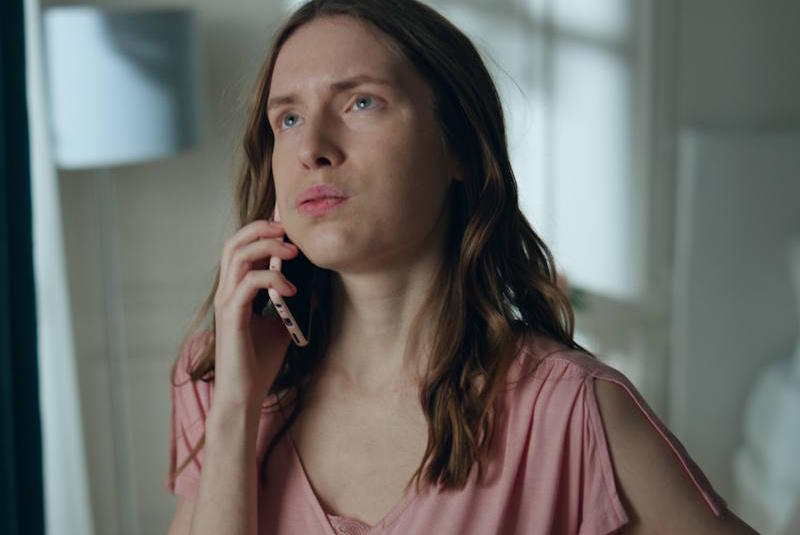 Woman holding a phone with a tense, reflective expression, illustrating emotional strain and misunderstanding during difficult relationship conversations.